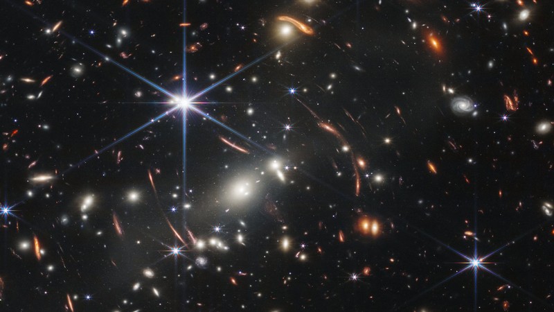 The background of space is black. Thousands of stars and galaxies appear all across the view.