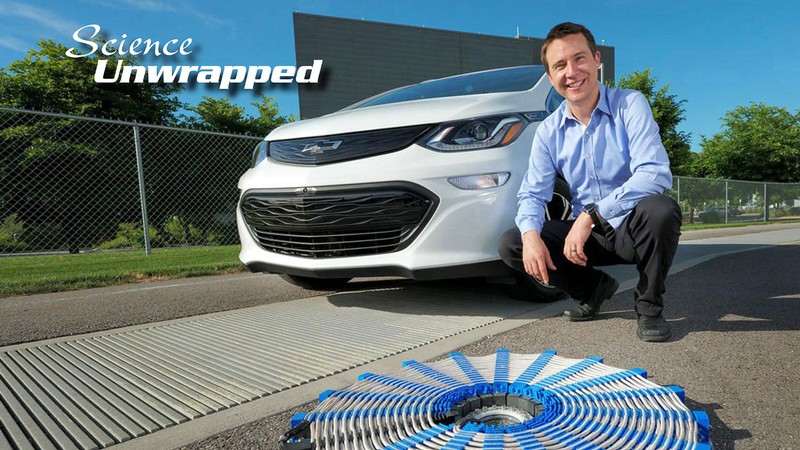 USU electrical engineer Regan Zane poses next to an electrical vehicle and experimental equipment.