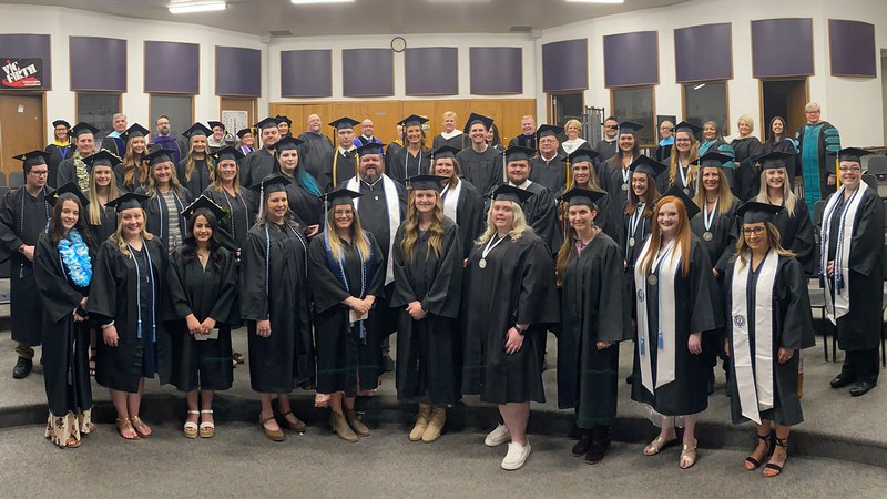 Graduates pose for a photo in their caps and gowns.