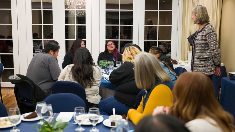 Noelle Cockett speaking with high schoolers at a dinner.