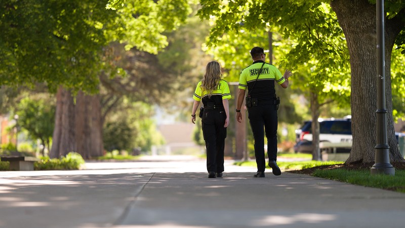 Two security officers walking on a sidewalk.