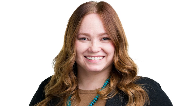A woman poses for a photo against a white background.