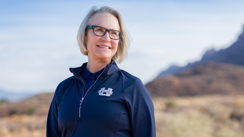 A woman smiles while being in a desert landscape.