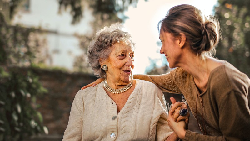 A woman talking with an older woman.