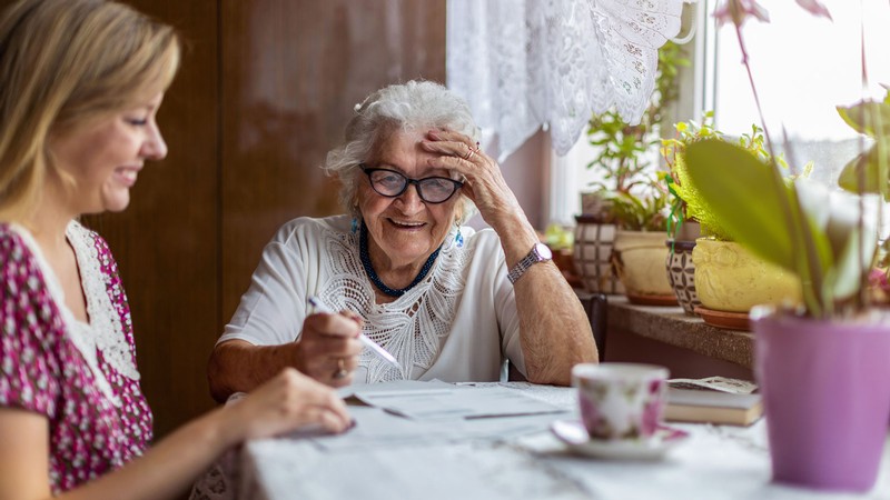 An older woman and younger woman sit at a table.