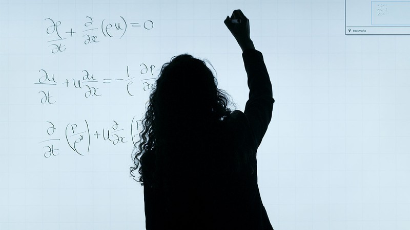 A person writing mathematical equations on a digital whiteboard.