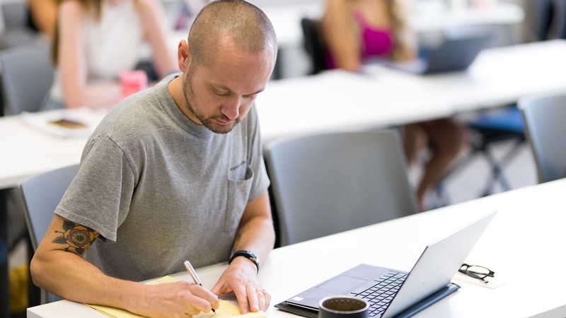 A person writing in a classroom.