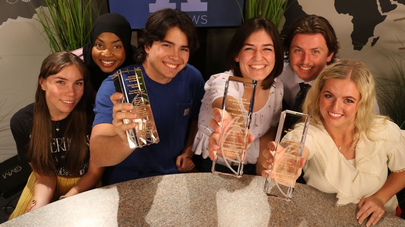 Student journalists holding awards.
