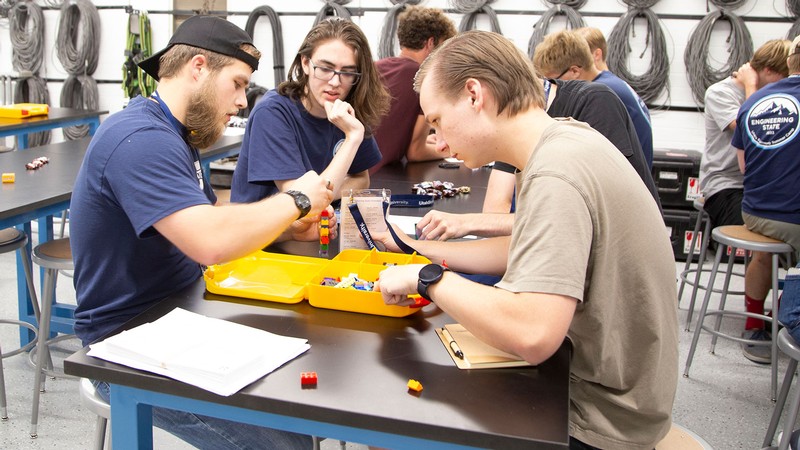 Students sit at a table building with lego bricks