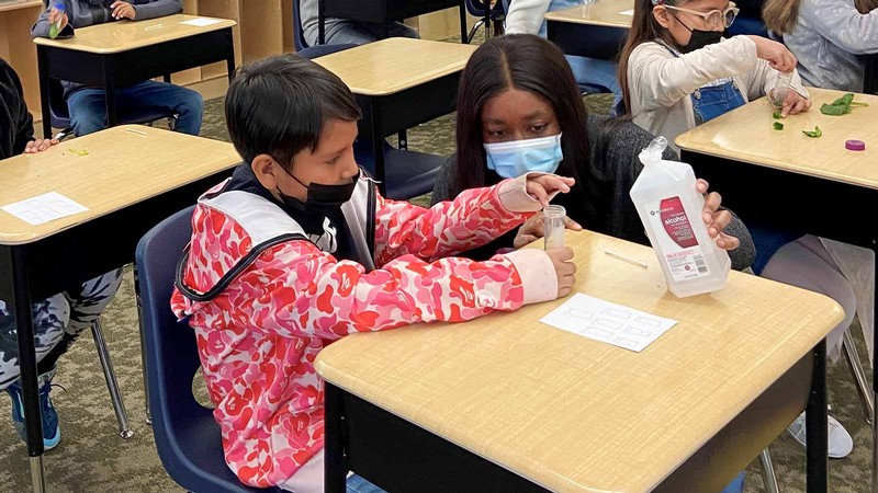 An engineering student demonstrates an experiment to a grade-schooler.