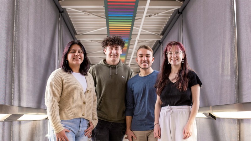 Students in front of a rainbow display.