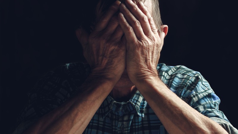 A person holding their head in their hands.