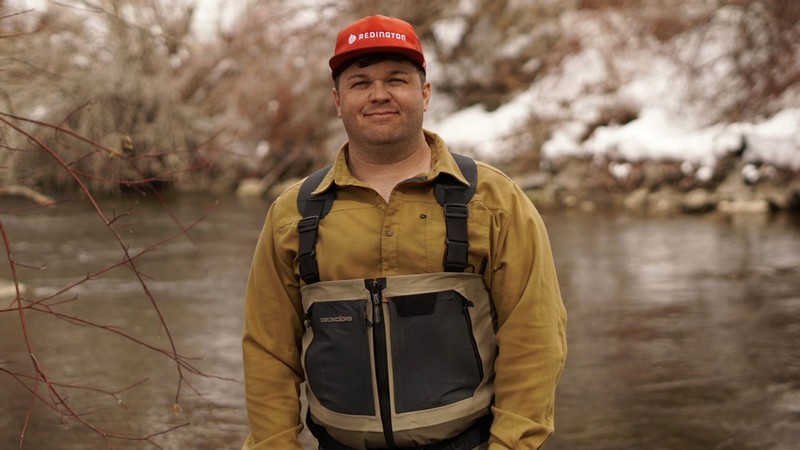 Tyler Coleman at a river in fly fishing apparel.