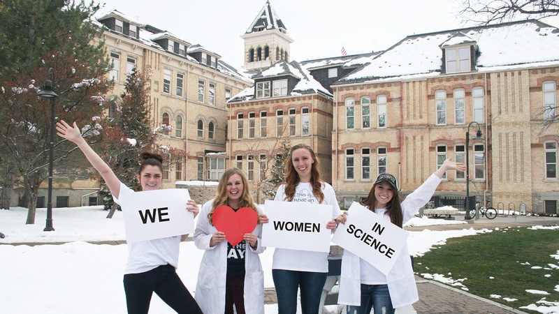 Women scientists holding placards reading "We love women in science."