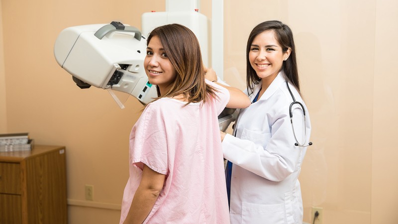 A doctor prepares a female patient for a mammogram.