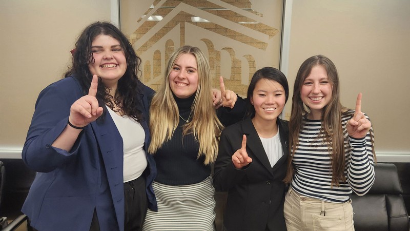 Women in business attire holding their fingers up to mean "number one."
