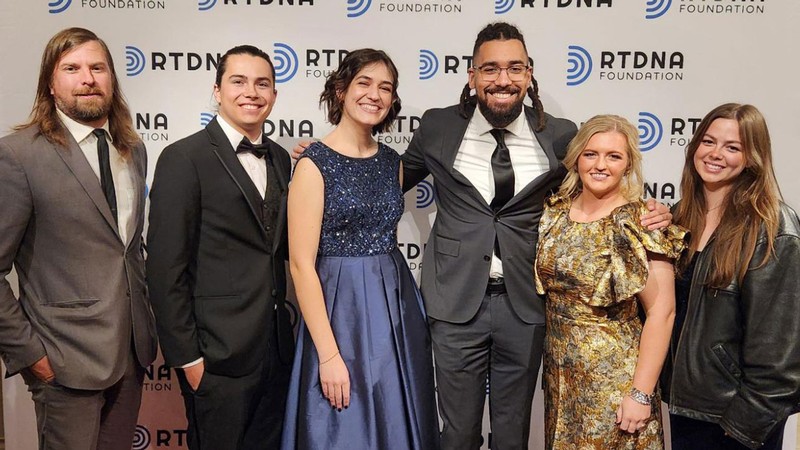 A professor and students pose for a picture at an awards ceremony.