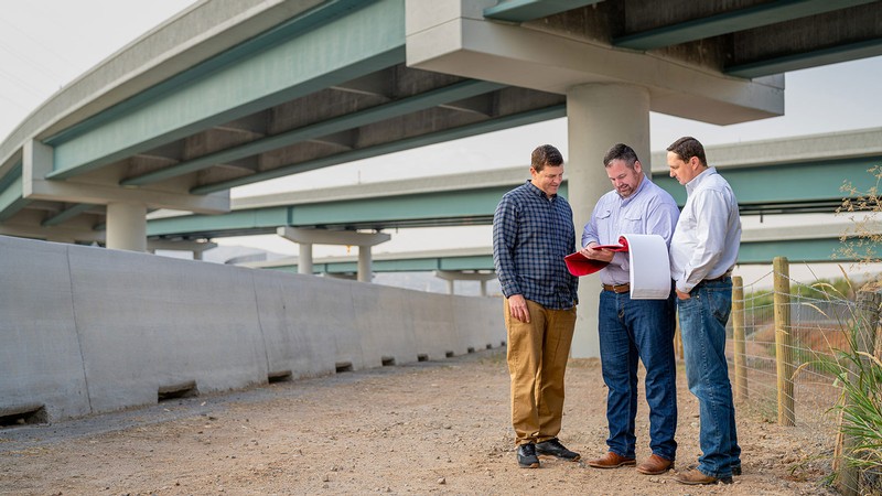 Engineers looking at plans near a newly completed freeway interchange.
