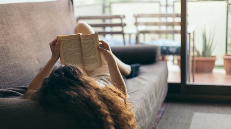 A person on a couch reading a book.