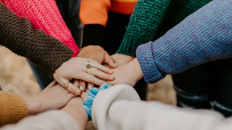 Several people putting their hands into a huddle.