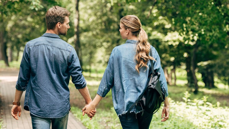 Two people holding hands while walking.