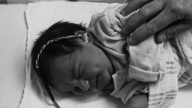 A newborn with an earbud in its ear.