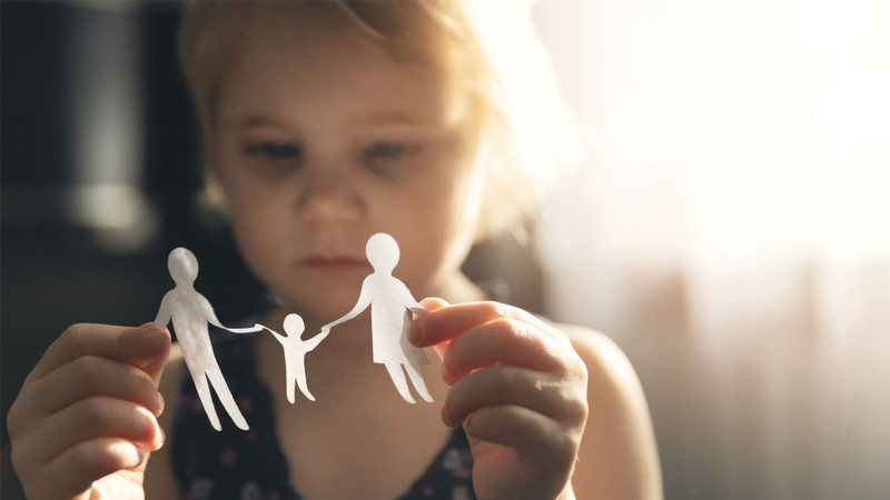 A girl playing with a paper-doll family.