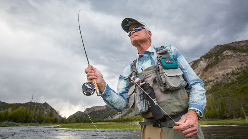 A fly-fisher wading in a river.