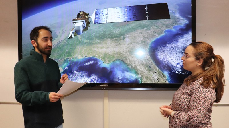 Computer Scientists standing by a video satellite image.