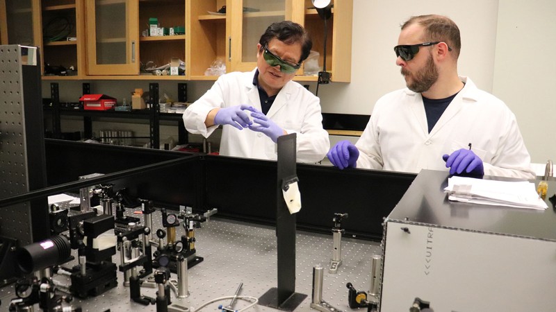 Yi Rao and Jesse Brown wearing protective equipment in a lab.