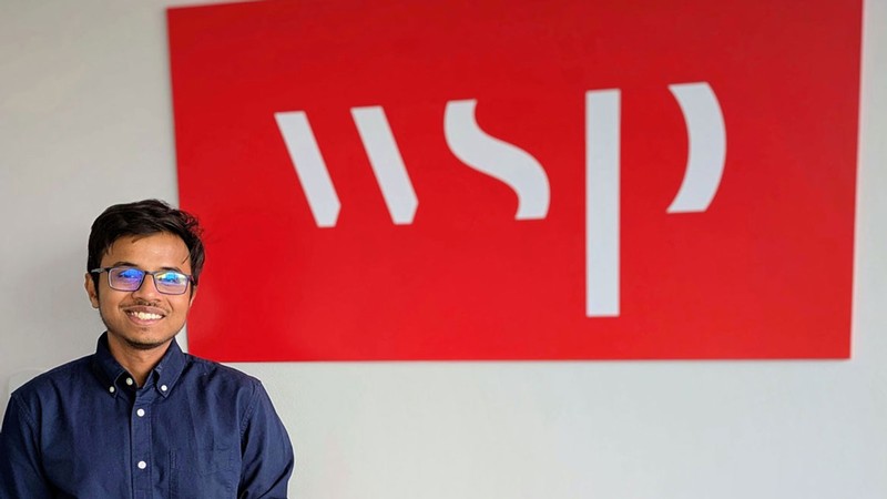 A man posing next to a sign with the letters WSP.