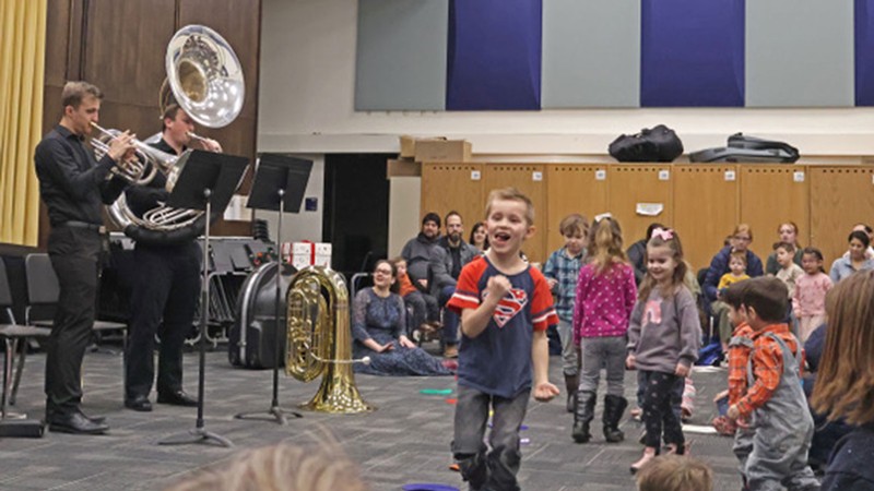 Children play while listening to orchestra musicians.