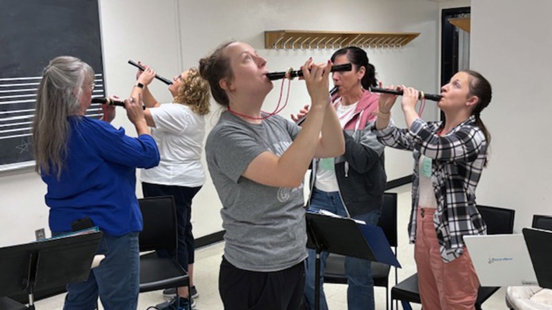 Teachers playing recorders in a classroom.
