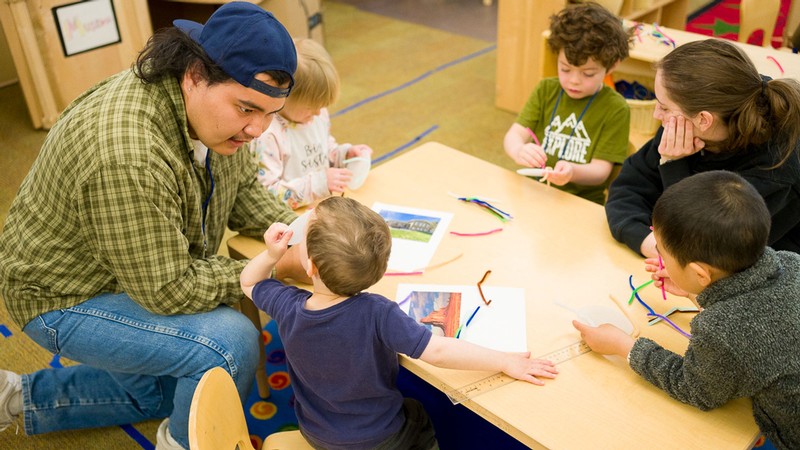 Adults talking with children in a classroom.