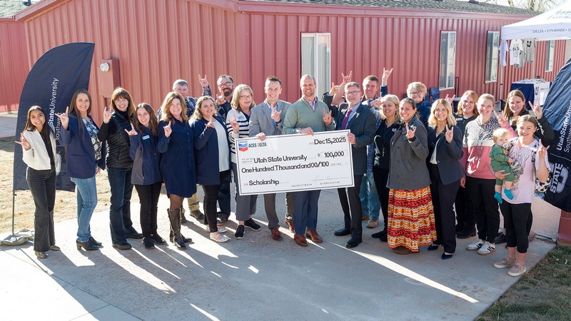 A group of people celebrate during a check presentation at the USU campus in Delta.