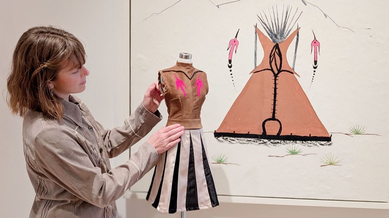 Abigail Budge with a half-size dress and a mural of a teepee.