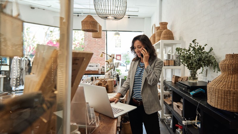 A woman using a laptop behind a store counter.
