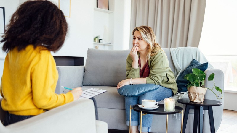 A woman talking to another woman while she fills out a form.