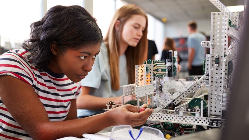 A young woman builds a small machine