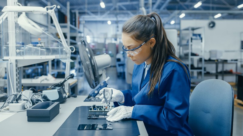 A woman working on a circuit board in a factory.