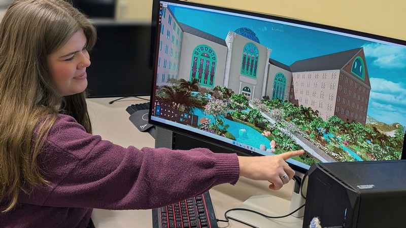 A student pointing to a landscape design on a computer monitor.