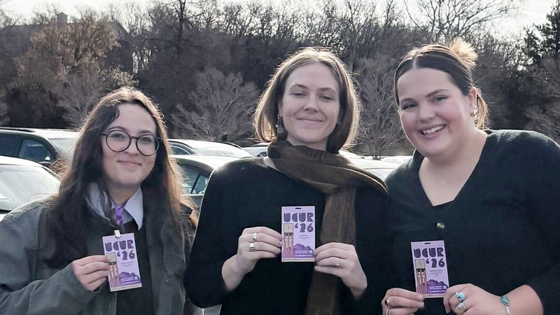 People standing in a parking lot with conference badges.