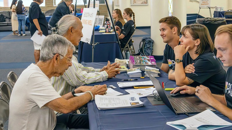 Researchers speaking with older adults at an event.