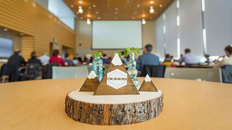 A wood and glass sculpture in the shape of trees and mountains with the letters MWEHC.