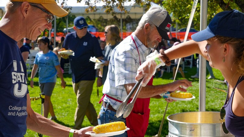A volunteer serves corn to an attendee at the Utah Ag Products BBQ.