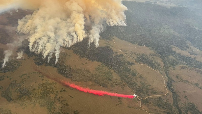 A plane dropping fire retardant near a wildfire.