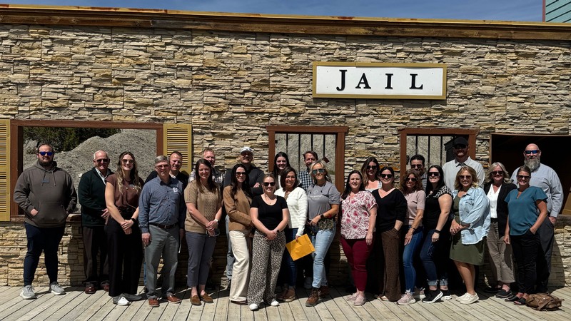 A group of people in front of a false jail facade.