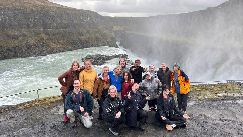 People posing for a photo in front of a waterfall.