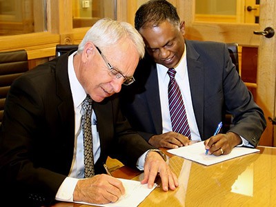USU President Stan Albrecht and President Spalding Jugganaikloo signing a partnership agreement