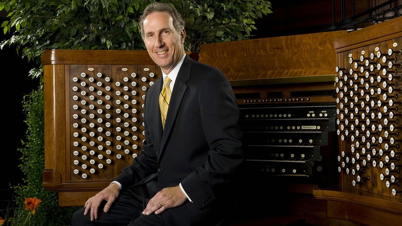 Richard Elliott poses in front of a pipe organ console.